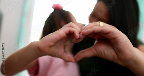 Mother and child doing heart symbol sign with hands © Marco