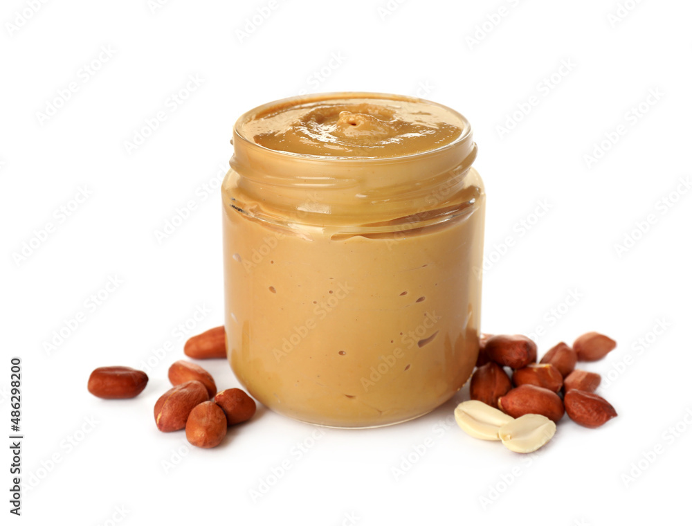 Glass jar of creamy peanut butter and nuts on white background Glass jar of creamy peanut butter and nuts on white background