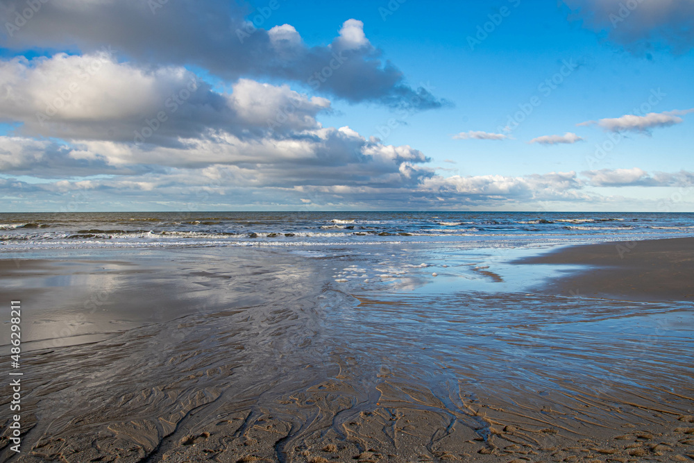 Wolken spiegeln sich im Wasser am Strand und Rinnsale im Sand  