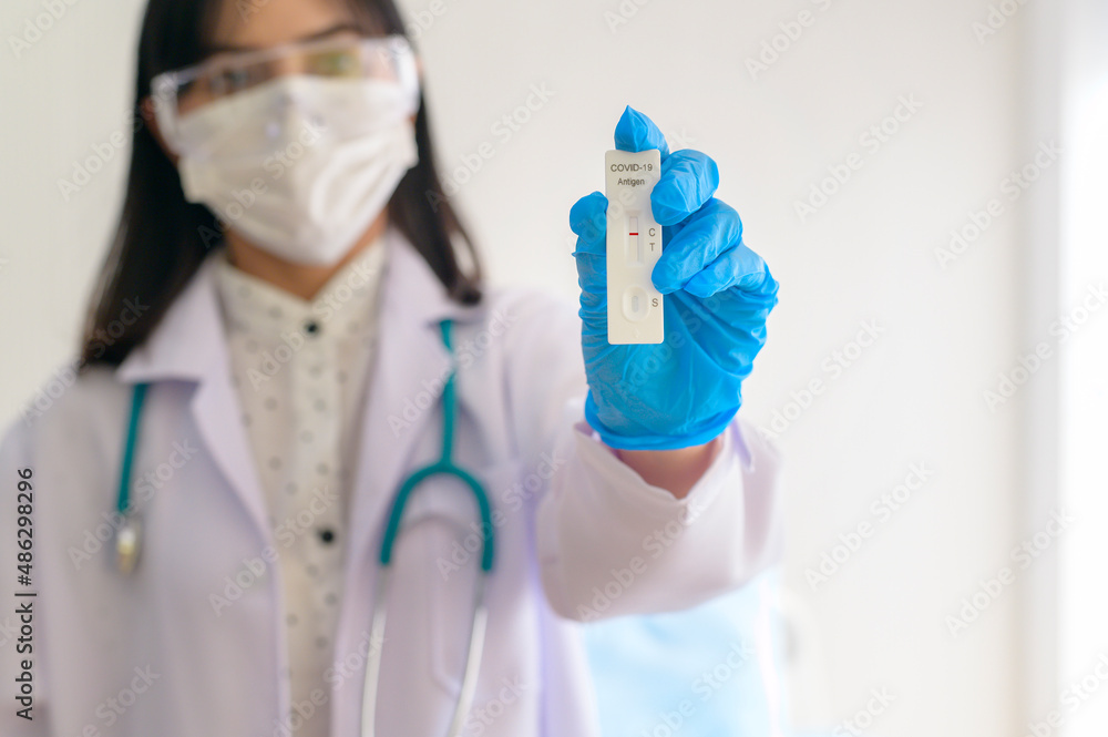 Fototapeta premium Young female doctor holding ATK kit in hospital, covid19 and pandemic concept