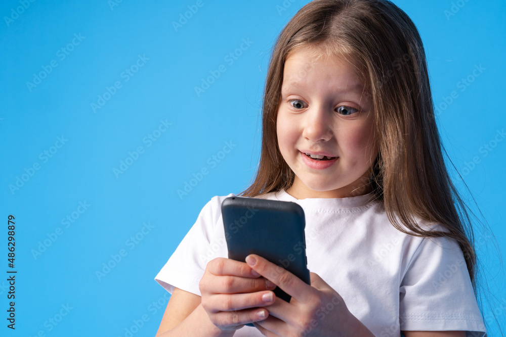 Little girl using mobile phone.against blue background Little girl using mobile phone.against blue background