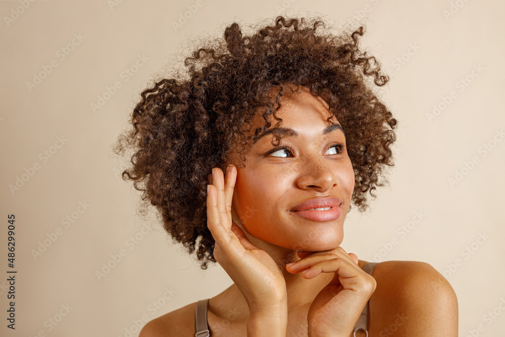 Charming multiracial lady posing against beige wall Charming multiracial lady posing against beige wall
