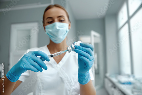 Woman doctor in laboratory holding a syringe with vaccines. Female holding COVID-19 vaccine in hand. Concept:diseases,medical care,science.