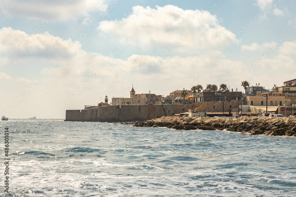 View from the boat to the Mediterranean Sea, the fortress wall and buildings in the old city of Acre in northern Israel