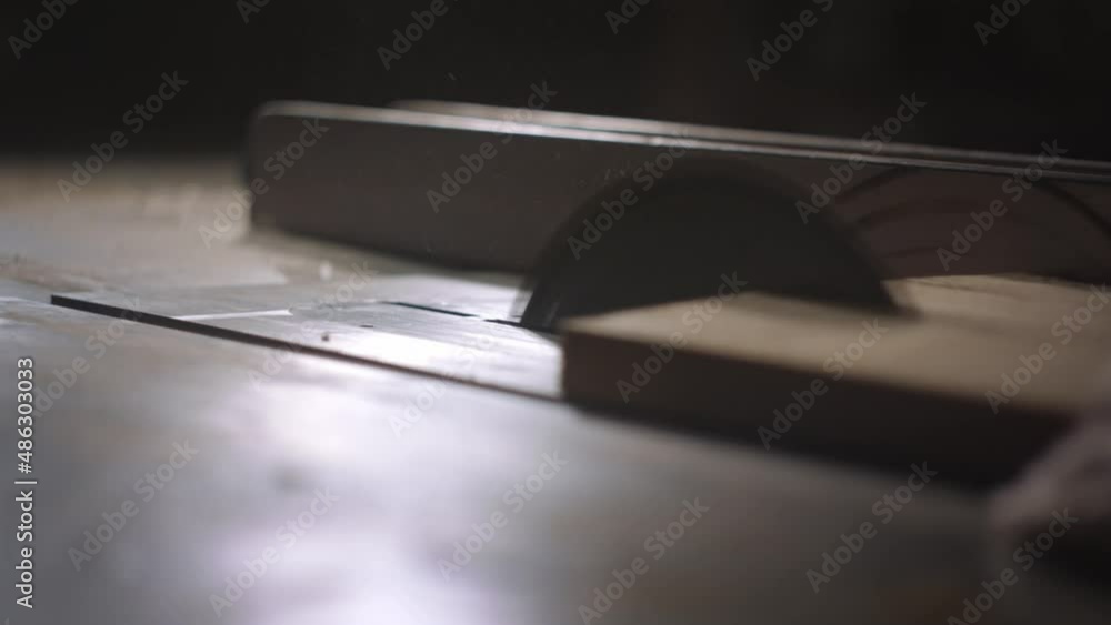 Carpenter working hard using a table saw, sending wood chips flying into the air in slow motion. Carpenter working hard using a table saw, sending wood chips flying into the air in slow motion.