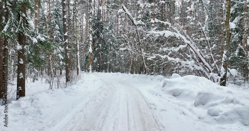 Flying a over a snow-covered, forest road, snow covered road in the forest