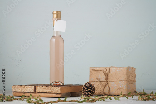 250 ml bottle of white or pink wine with blank label. Wrapped Christmas present, pine cones. Alcohol drink. Copy space