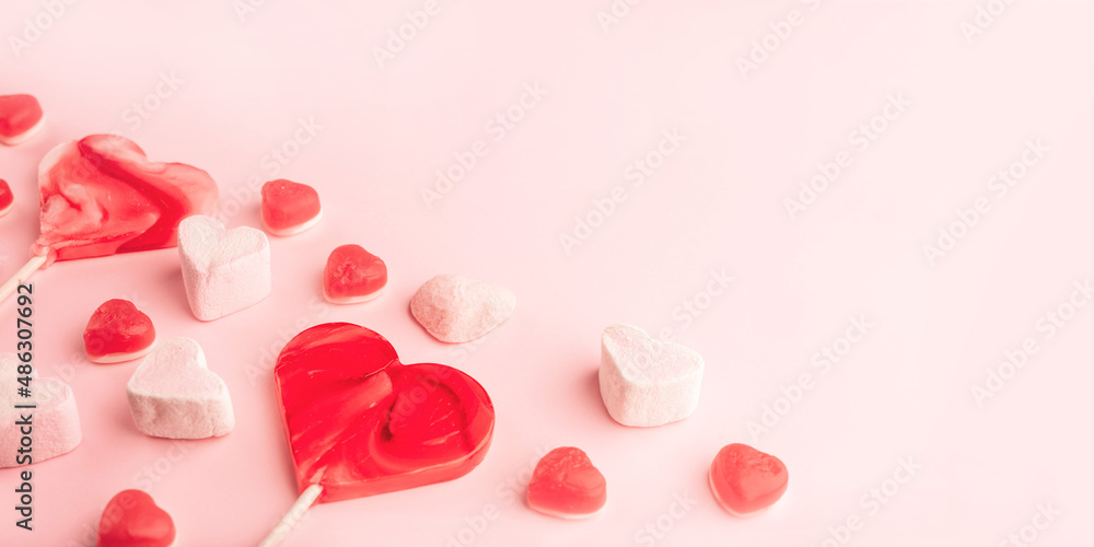 Pink romantic holiday backdrop with heart-shaped sweet candies. Decorative card for St. Valentine's Day with space for text.