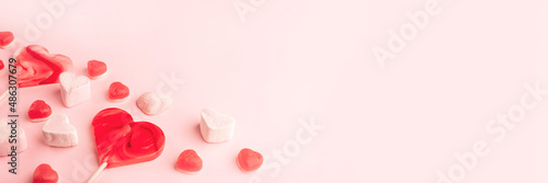 Pink romantic holiday banner with heart-shaped sweet candies. Decorative card for St. Valentine's Day with space for text.