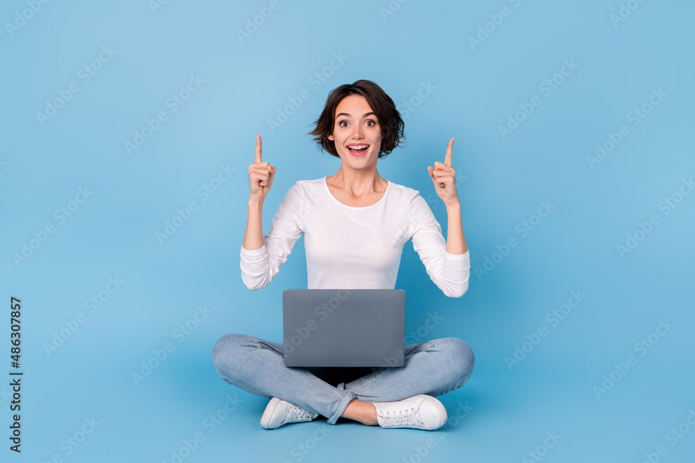 Photo of cute excited lady dressed white shirt legs crossed empty space typing modern device isolated blue color background Photo of cute excited lady dressed white shirt legs crossed empty space typing modern device isolated blue color background