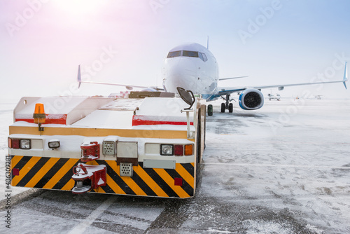 Tow tractor pushes the passenger aircraft at the cold winter airport apron