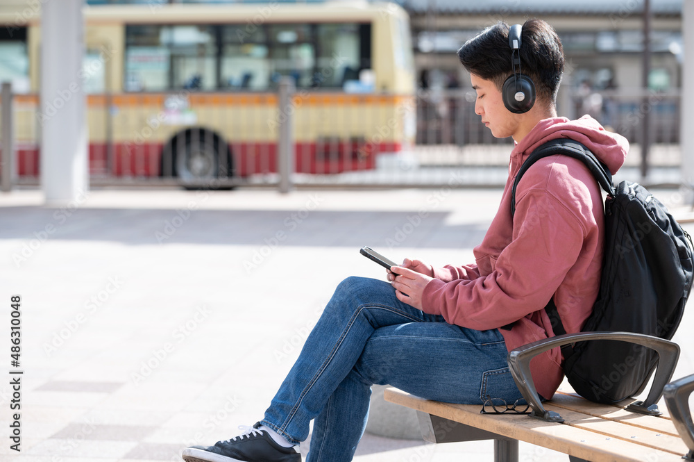 音楽を聞いてベンチに座る青年 音楽を聞いてベンチに座る青年