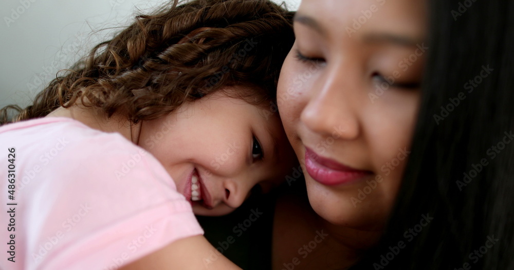 Asian mother cuddling with little daughter in arms, love and affection Asian mother cuddling with little daughter in arms, love and affection