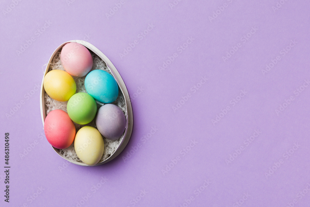 Multi colors Easter eggs in the woven basket on colored background . Pastel color Easter eggs. holiday concept with copy space Multi colors Easter eggs in the woven basket on colored background . Pastel color Easter eggs. holiday concept with copy space