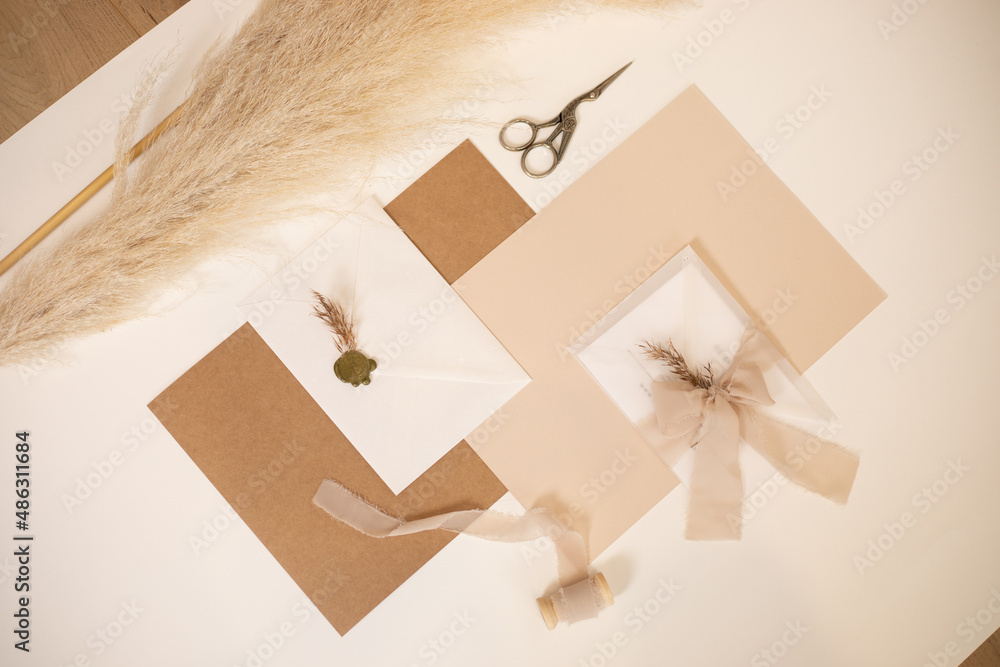Pastel beige mock up composition of paper envelopes with ribbons, herb. scissors, cut out handmade jobbing. Top view. Pastel beige mock up composition of paper envelopes with ribbons, herb. scissors, cut out handmade jobbing. Top view.