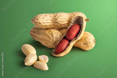set of peanuts in a nutshell, unpeeled and peeled peanuts on a green background with a shadow.