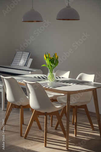 Sunny lights in white living room with fresh flowerson table