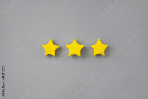 Three golden star on neutral background. Golden star shape. Concept of top class, best quality product symbol. Sign of evaluation or feedback from customer.