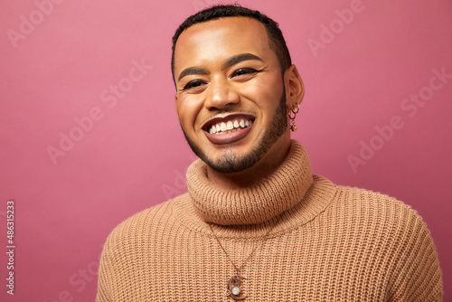 Studio portrait of smiling queer man against purple background photo