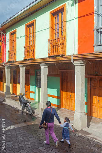 Indigenous woman with child walking to school in front of colonial style architecture, Quito, Ecuador. photo