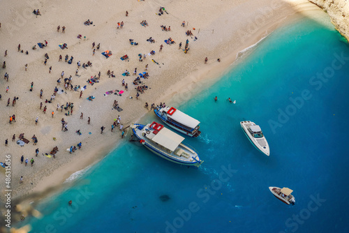 Zakynthos, Greece Navagio Shipwreck beach with crystal clear waters. Panoramic view of moored leisure boats and bathers on famous Ionian Island beach, once voted as best in the world.