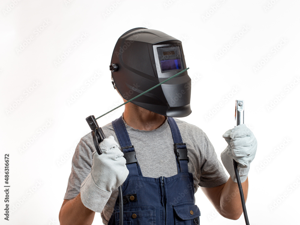 A man in a welding mask, robotic clothes and gloves, holding a wire with a welding electrode. A man in a welding mask, robotic clothes and gloves, holding a wire with a welding electrode.