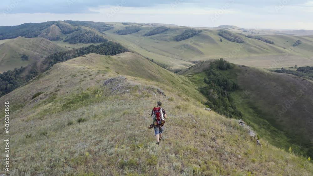 The hiker with a backpack walking along the top of the hill. The hiker with a backpack walking along the top of the hill.