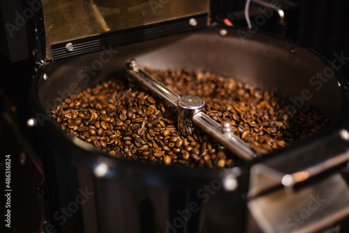 Brown roasted coffee beans in a coffee grinder. Preparation of coffee beans. Coffee business.