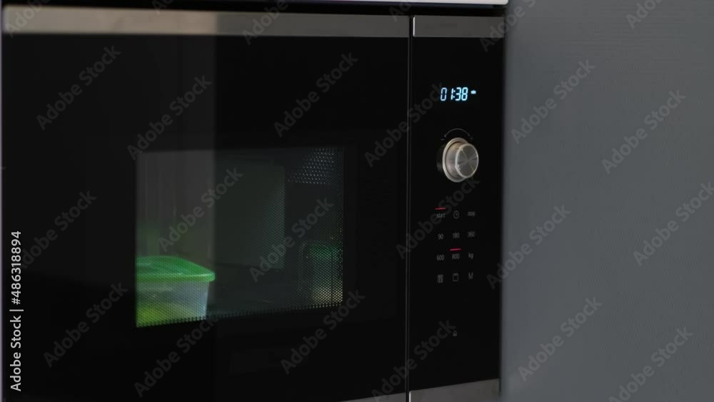 woman hands warming up a container of food in the modern microwave oven for snack lunch at home woman hands warming up a container of food in the modern microwave oven for snack lunch at home