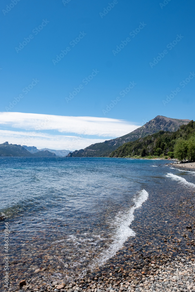 View of the Lake in the mountains in spring. Patagonian Coast Lake. Waves on the coast. Peninsula. Vertical Panoramic View. Vertical photo.