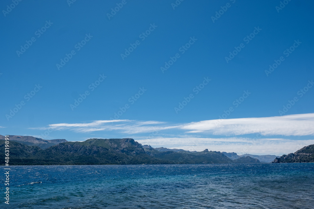 View of the Lake in the mountains in spring. Patagonian Coast Lake. Waves on the coast. Peninsula. Vertical Panoramic View. Vertical photo.