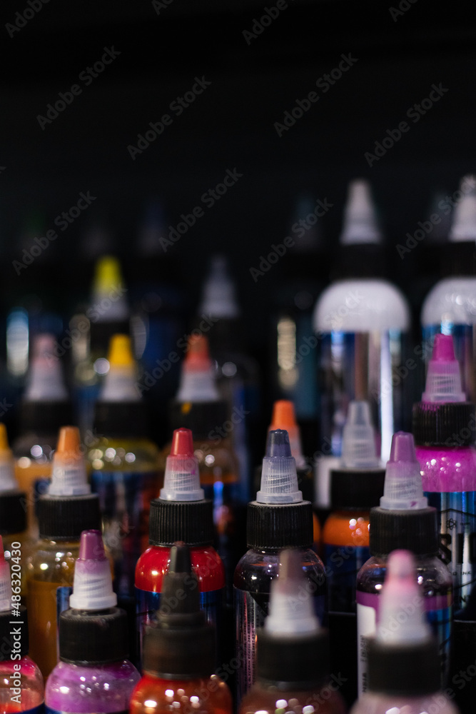 Bottles of multicoloured tattoo inks. Tattoo salon. Selective focus, blurred. Bottles of multicoloured tattoo inks. Tattoo salon. Selective focus, blurred.
