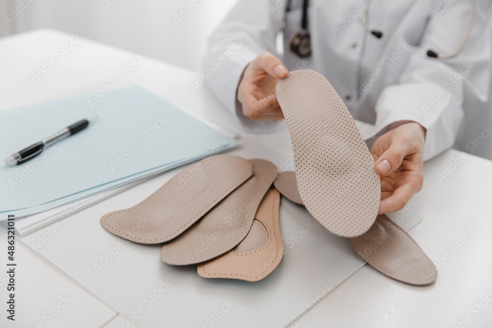 Doctor holding an insole while sitting at a table. Orthopedist tests