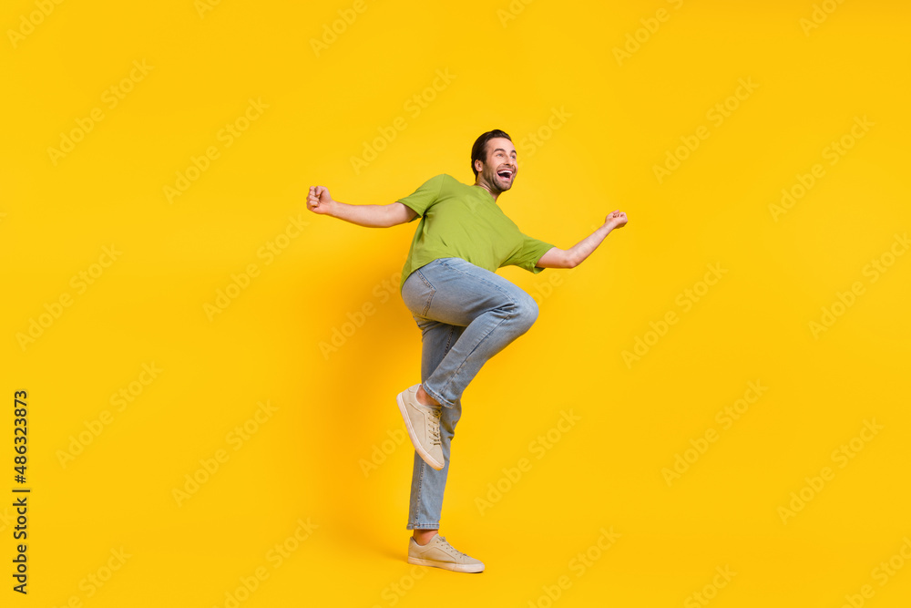 Full body profile side photo of young man good mood dancing look empty space isolated over yellow color background