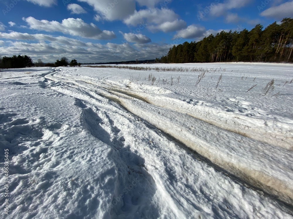Winter dirt road along the forest. Winter landscape.