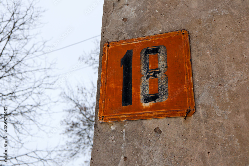 rusty house number eighteen on a concrete wall rusty house number eighteen on a concrete wall