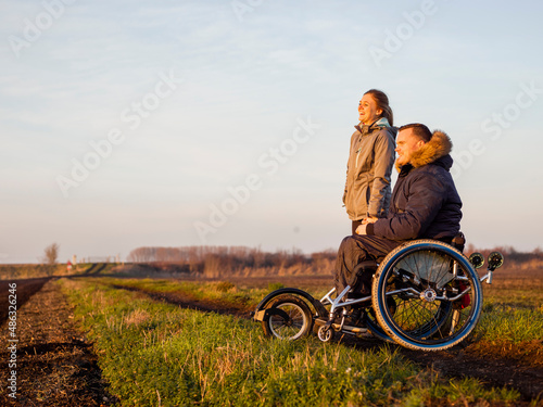 Smiling woman and man on wheelchair in field