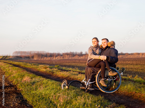 Smiling man on wheelchair in field with woman on laps