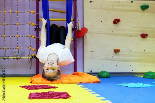 child girl in a hammock at the children's center for children with special needs and correction is undergoing a course of rehabilitation treatment autism flight coup