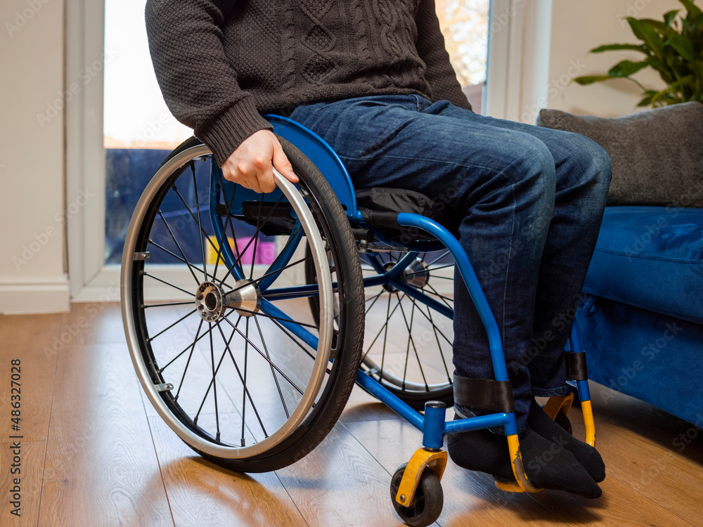 Obraz premium Low section of disabled man sitting on wheelchair at home