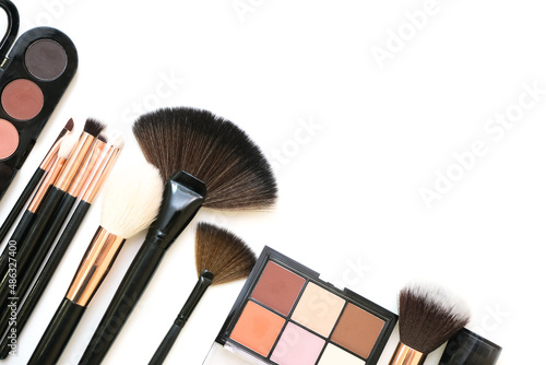 Decorative cosmetics and makeup brushes on a white isolated background, top view. place for your text