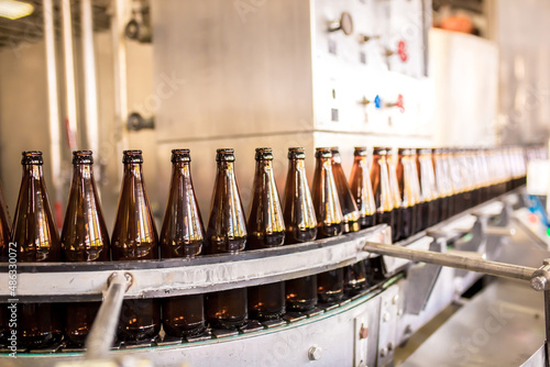 Brewery factory spilling beer into glass bottles on conveyor lines. Industrial work  automated production of food and drinks. Glass products. Bottles for drinks. Technological work at the factory.