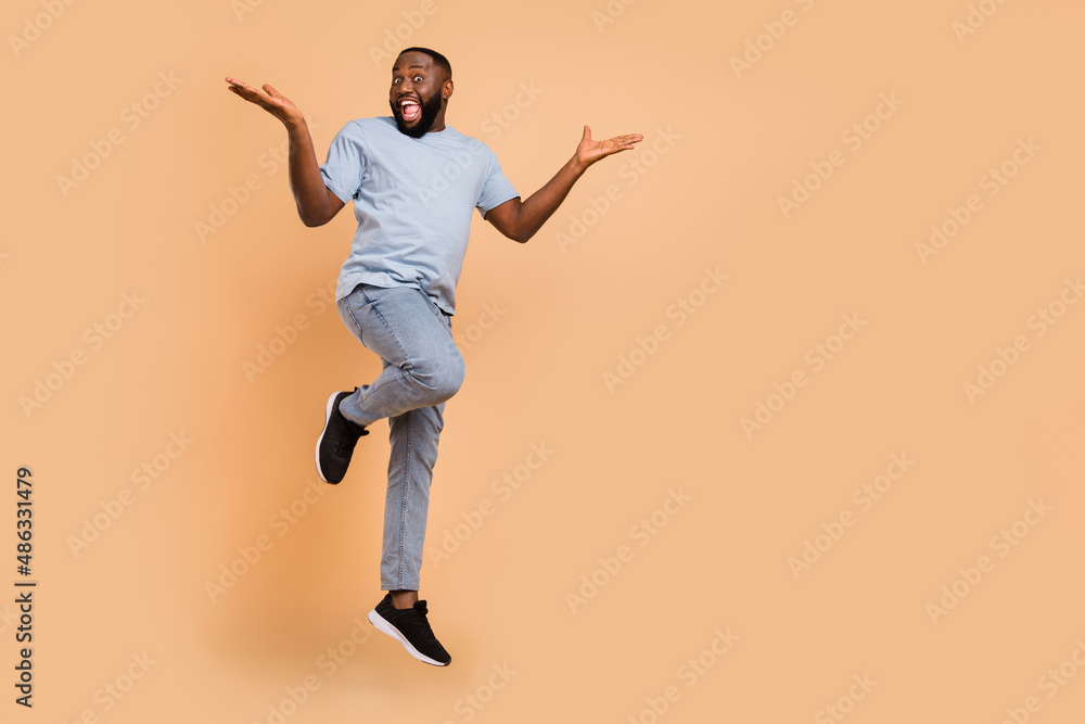 Full length body size view of attractive cheerful lucky guy jumping rejoicing copy space isolated over beige pastel color background