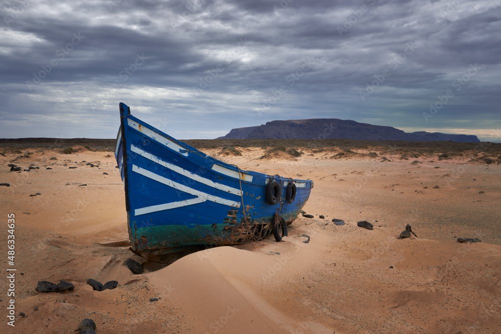 landscape with a blue and white boat stranded on the beach in the foreground and with a volcan in the background, dramatic clouds in the sky landscape with a blue and white boat stranded on the beach in the foreground and with a volcan in the background, dramatic clouds in the sky