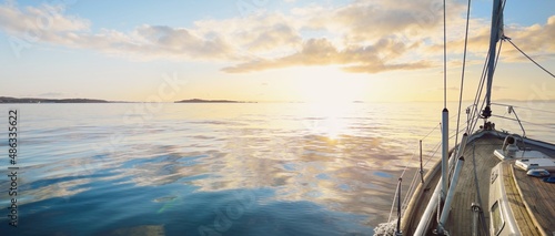 Konstfotografi Sloop rigged modern yacht with wooden teak deck sailing at sunrise