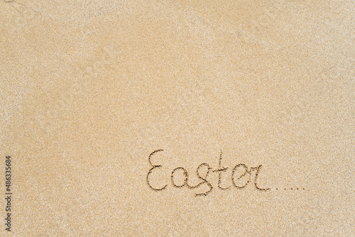 Drawing easter word on the sand on the beach.