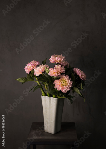 Spring background. Dahlias in pink in a glass vase on a gray background.