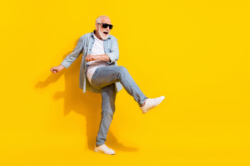 Full length body size view of attractive cheerful crazy grey-haired man dancing having fun isolated over bright yellow color background