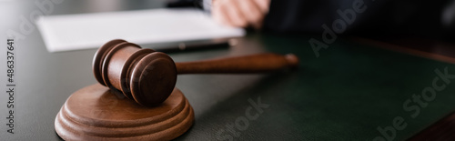 Photo wooden gavel on desk near cropped judge on blurred background, banner