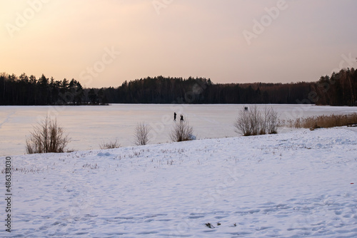 Snow-covered lake shore under ice at sunset